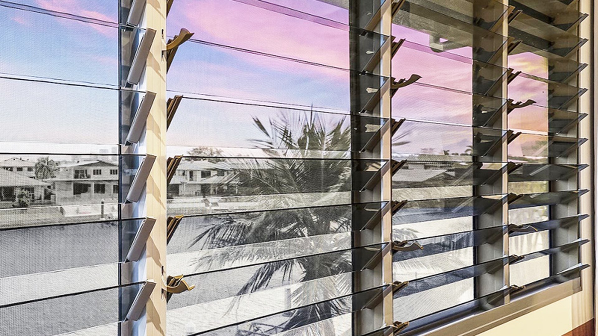 An adjustable louvre array installed across a balcony opening: the blade angle is set at the carrier rather than on site, which is what lets one elevation follow the sun.