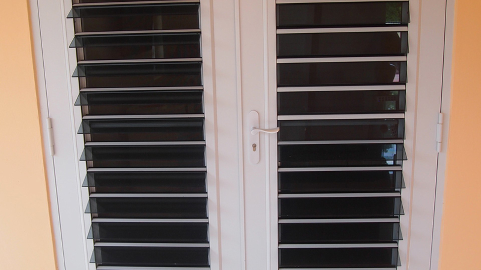 A white-framed glass louvre window with its blades open: each blade is a glazed unit in its own frame, which is why a glass louvre is a glazing specification as much as a shading one.