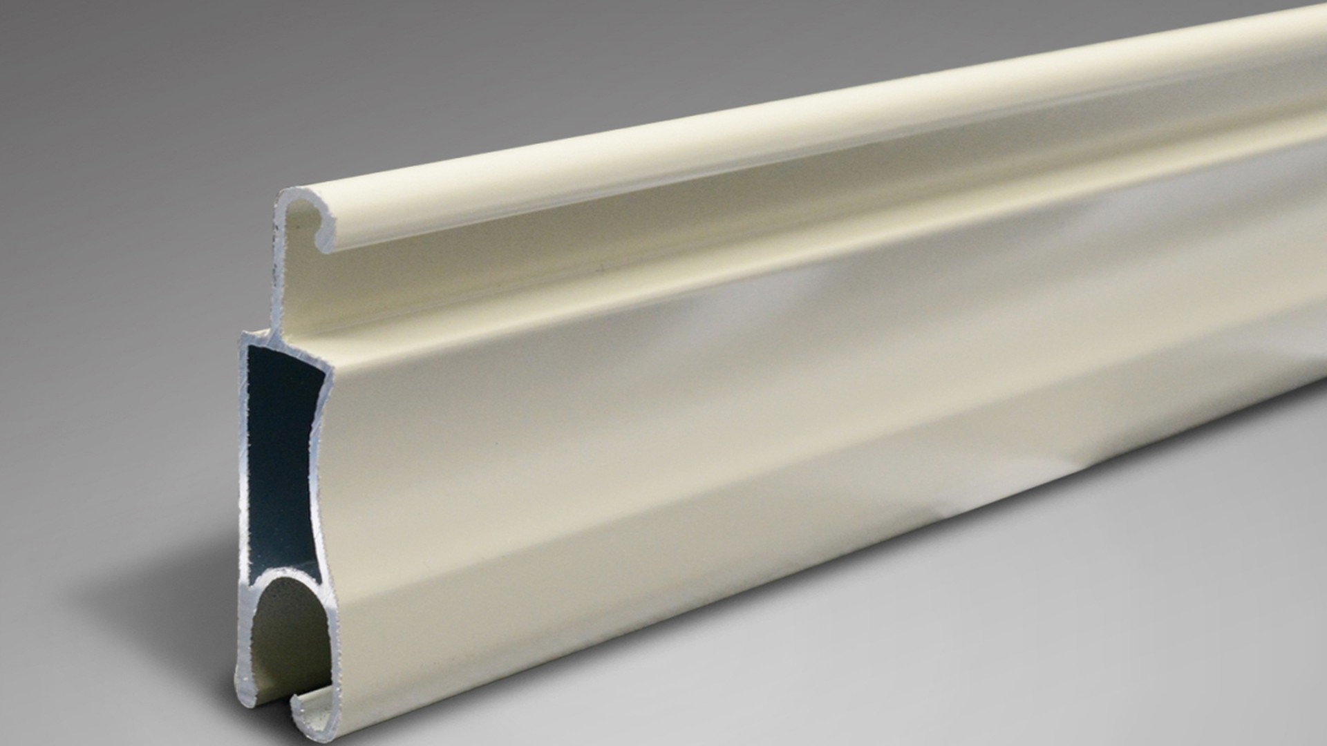 A cream-finished slat profile photographed on its own: finish and alloy are specified together, because a coated slat that corrodes at the cut edge fails long before the curtain does.