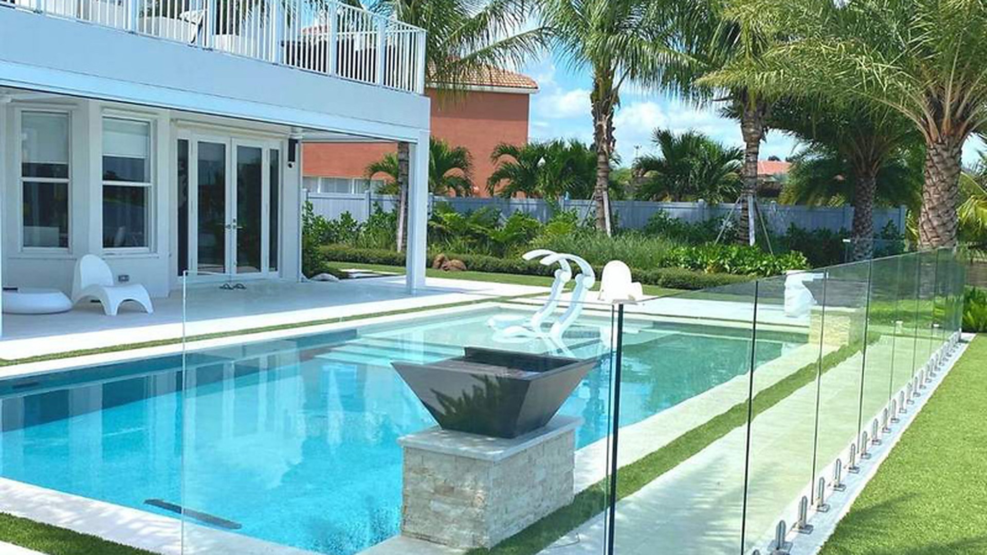 A resort pool enclosed by a frameless glass fence on spigots: a hospitality installation where the guard has to survive chlorine, sun and constant cleaning as well as the line load.