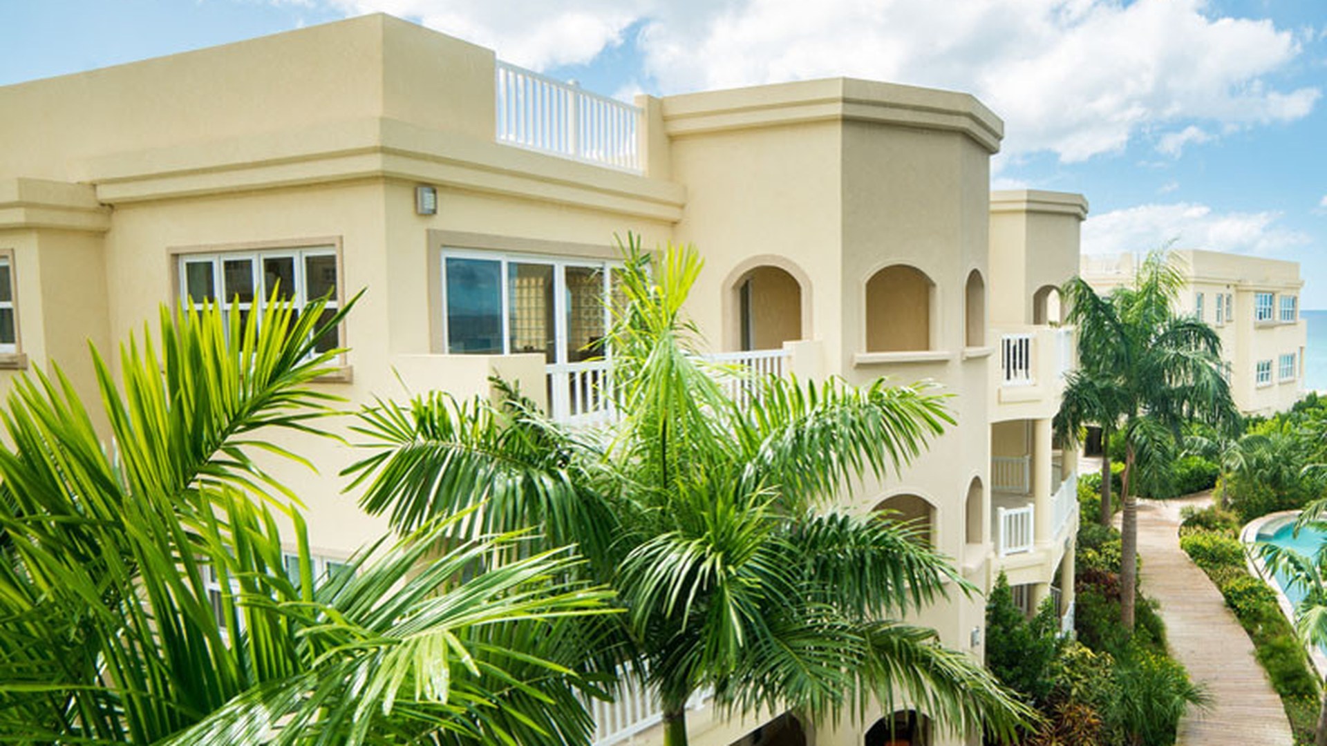 A multi-storey coastal residence behind palms: salt air, driven rain and a fully exposed elevation are the conditions a coastal sliding window is specified for, not a showroom.