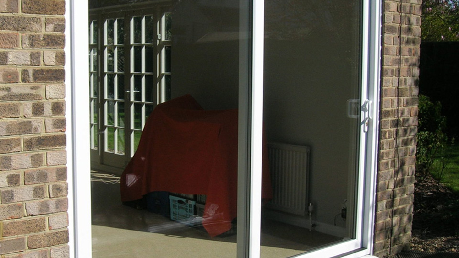 An installed two-panel slider seen from outside: the outer frame, the sash overlap and the threshold are the three places a coastal installation is judged on.