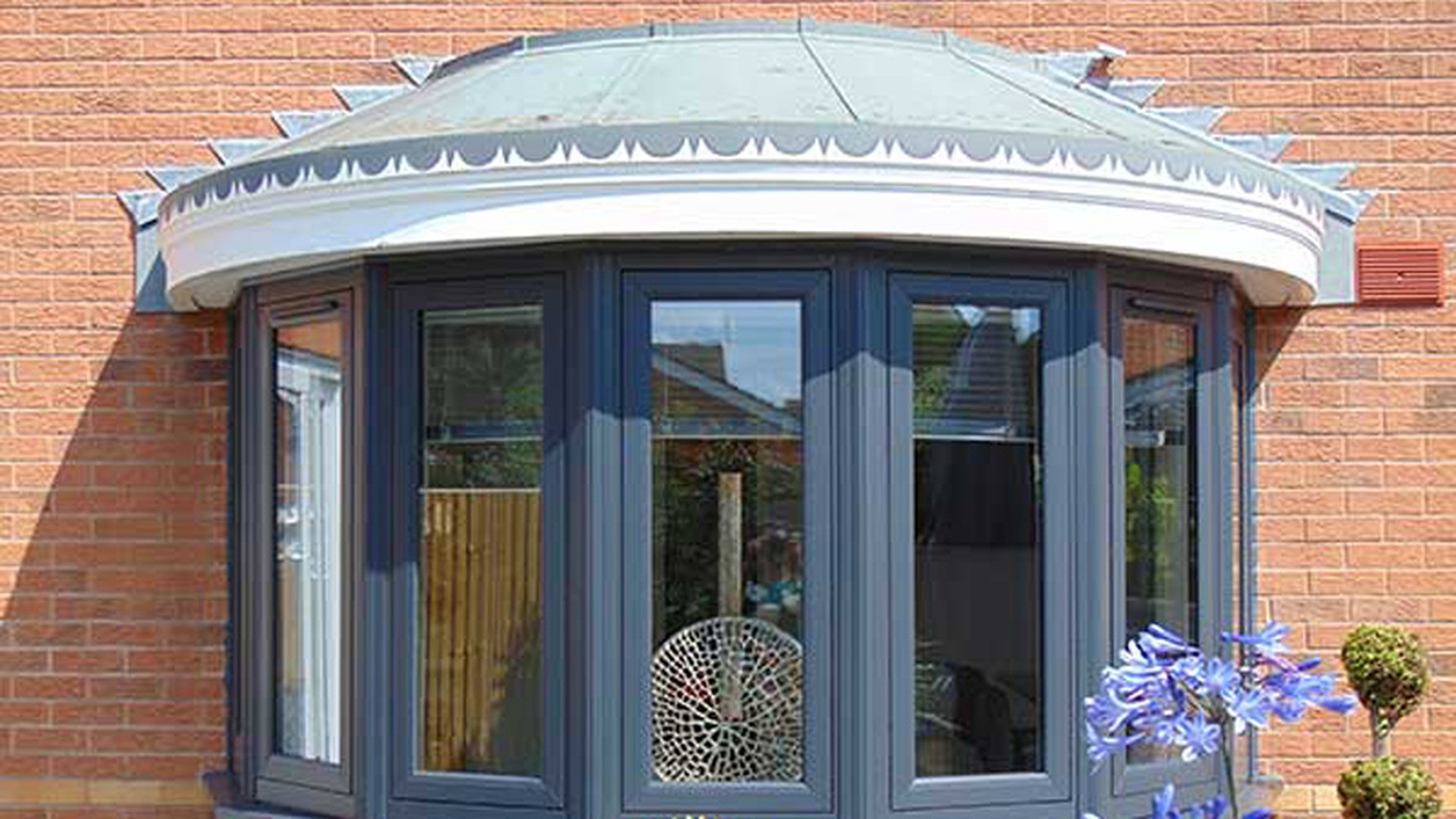 A bow window is a bay built on a curve: five panels set on an arc, with a curved canopy above. Neither the roof nor the interior sill can be cut from straight stock.