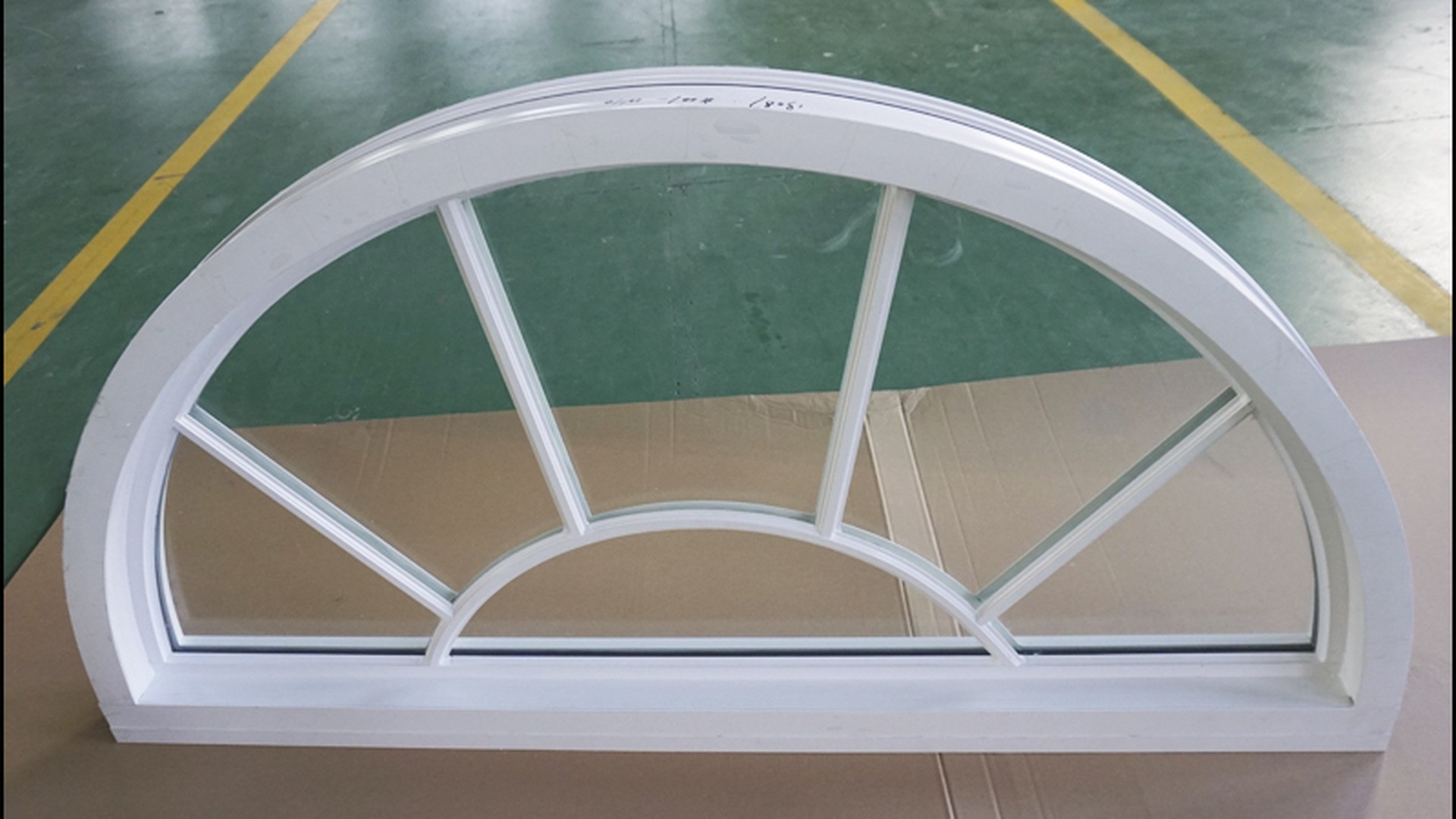 A fixed unit in the factory before packing: the arched head, the fan bars dividing the glass and the glazing rebate are all part of one frame, because nothing here opens.