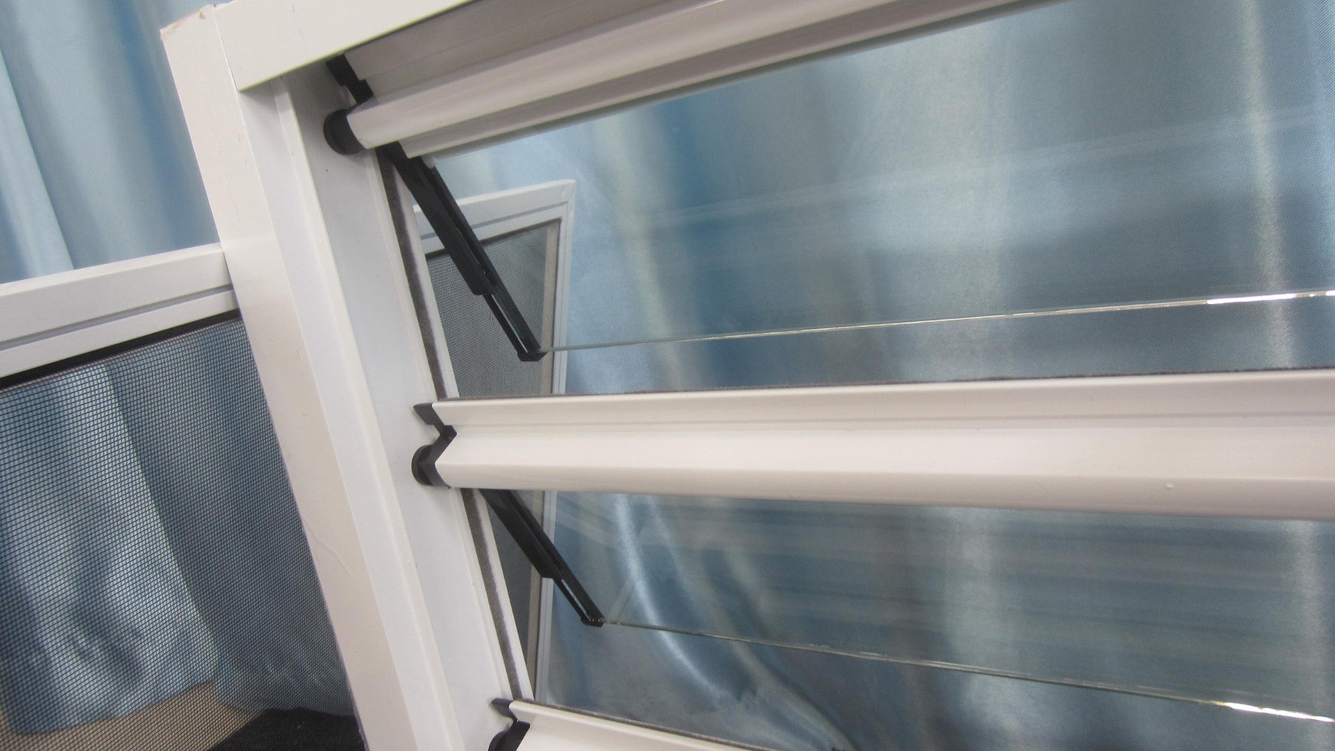 A pivot and its arm at the frame corner: every blade in an adjustable bank turns on the same linkage, so one worn shoe shows up as a blade that no longer lines up.