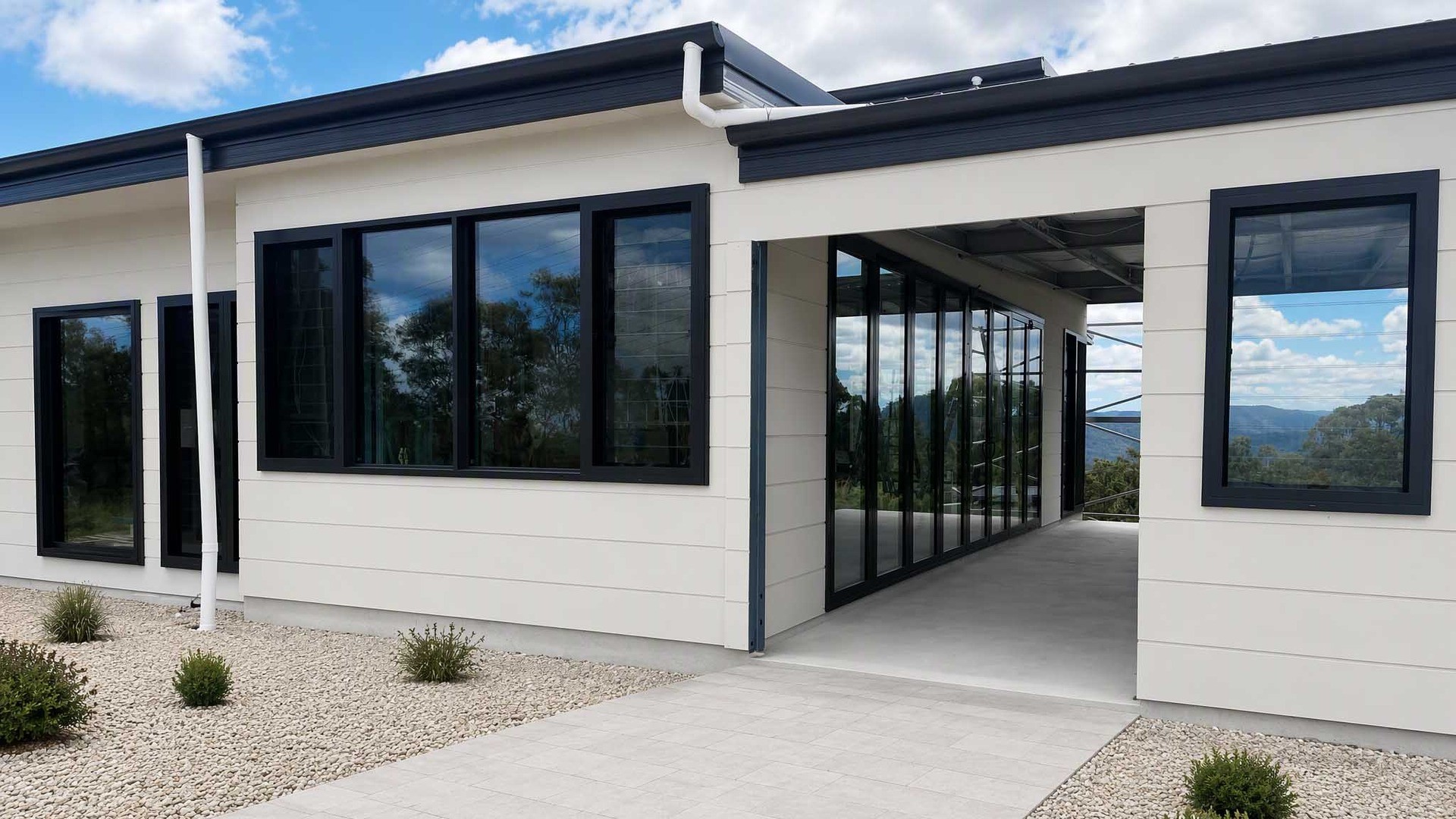 A completed elevation in black powder-coated aluminium: louver bands are usually read against fixed and sliding glazing on the same facade, and frame depth, colour batch and fixing detail are settled together.