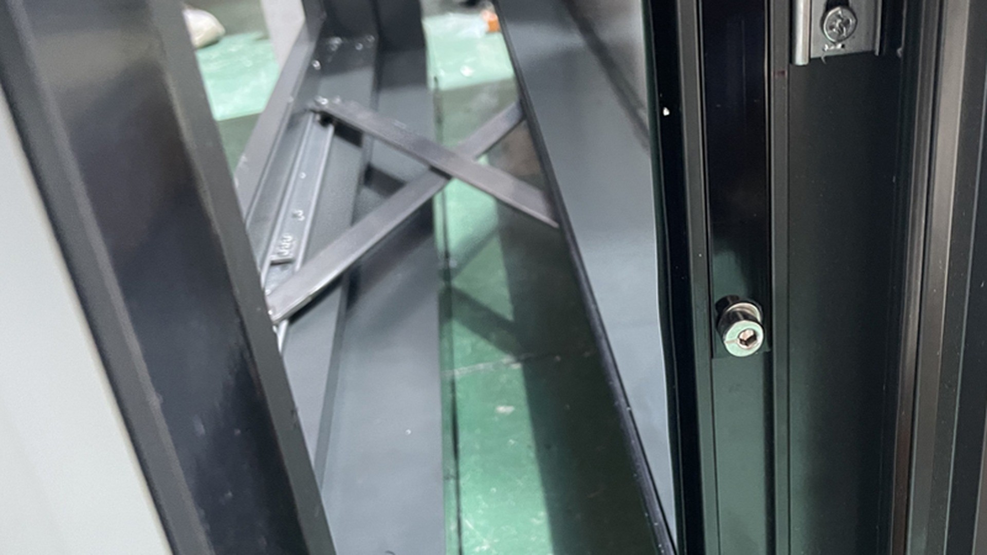 At the sash corner of a parallel opening unit: two friction stays meet the frame, the locking cam sits below them, and the whole vent hangs on hardware rather than on a pair of hinges.