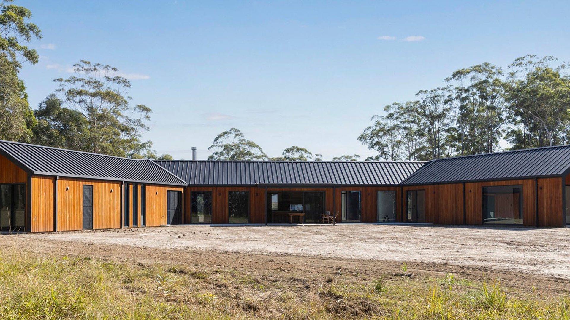 A long low commercial building with a continuous band of dark aluminium windows: the horizontal rhythm that decides how a parallel opening module is sized and where the mullions fall.