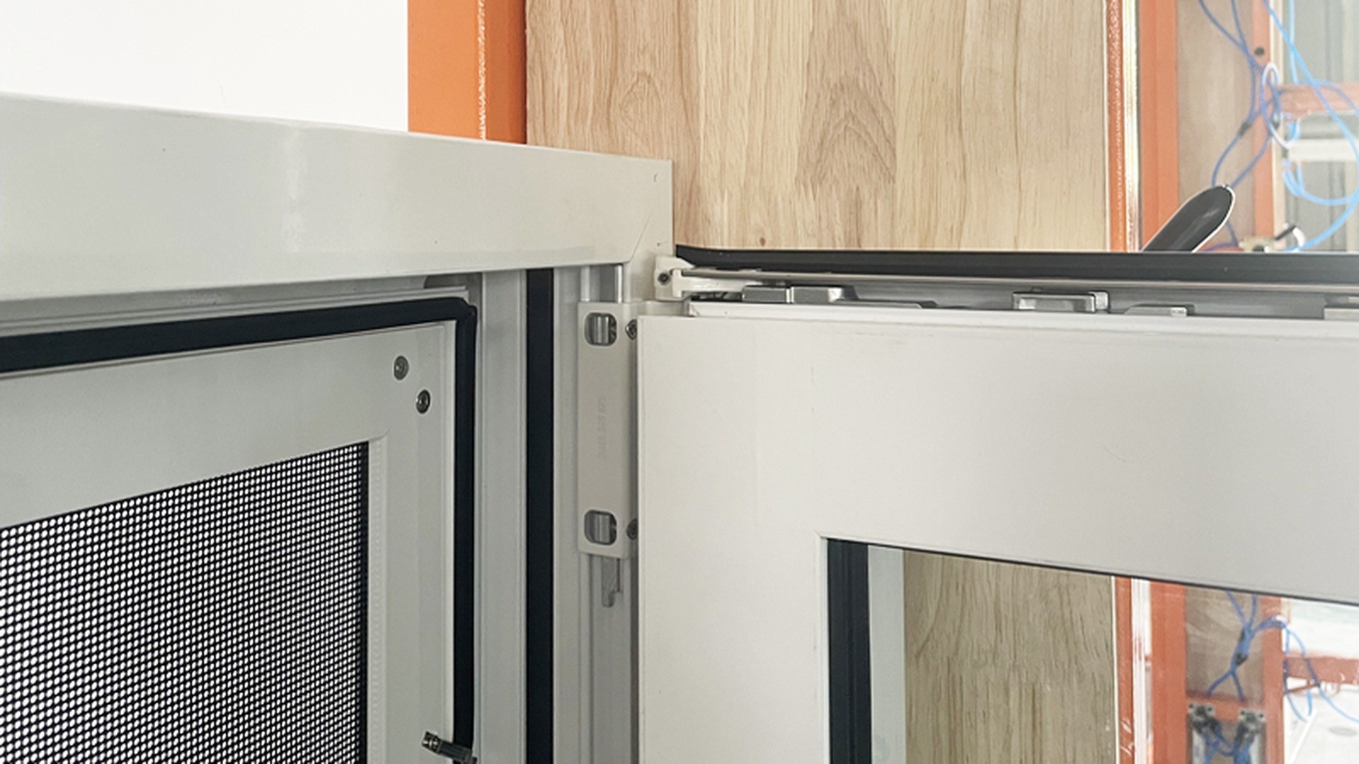 Head detail of an opening sash: the retractable flyscreen cassette sits behind the frame line and the upper stay is fixed to the sash head, the two components that decide whether a parallel vent can be screened.