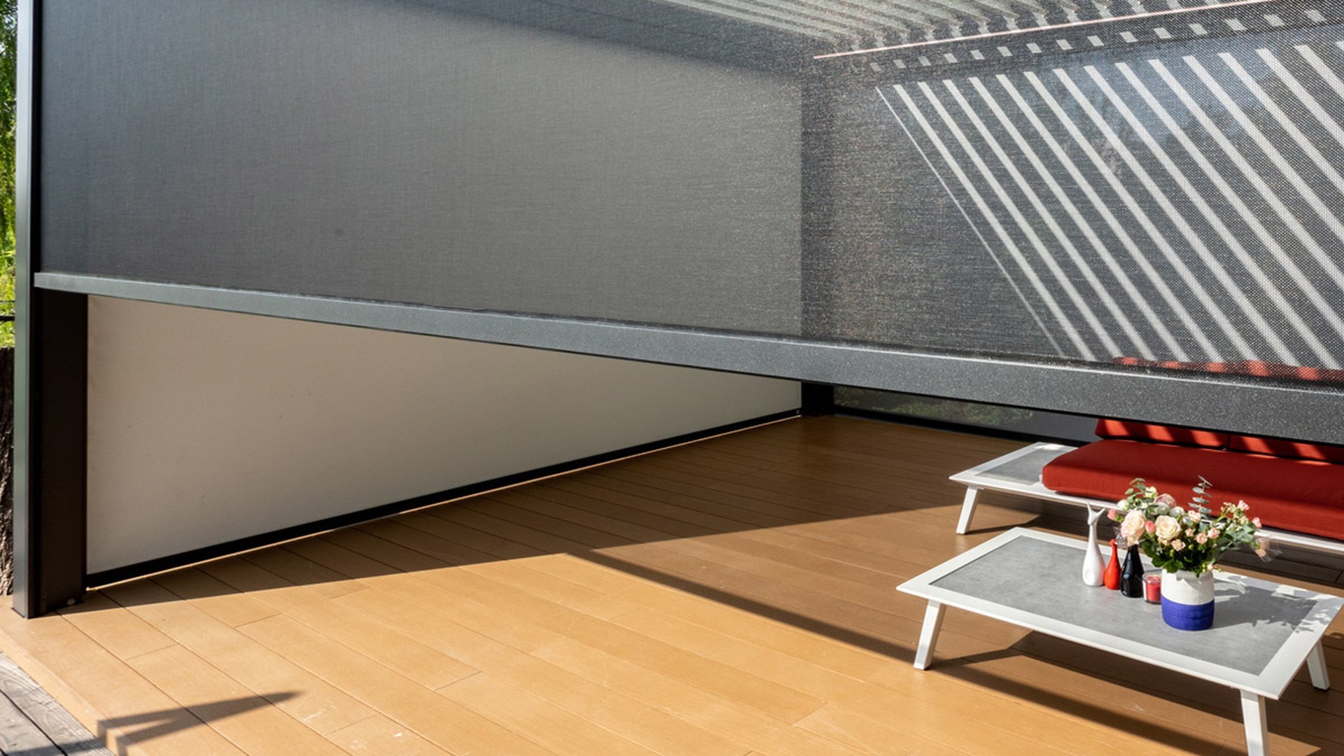 Mesh zip screens drawn down on a pergola: external shading keeps the sun off the glass, while an integral blind deals with the light after it has already entered.