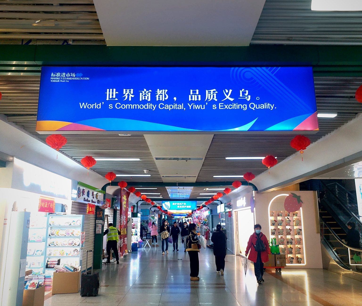 Interior of a large indoor trade market with rows of product booths — the scale of a wholesale sourcing hub like Yiwu