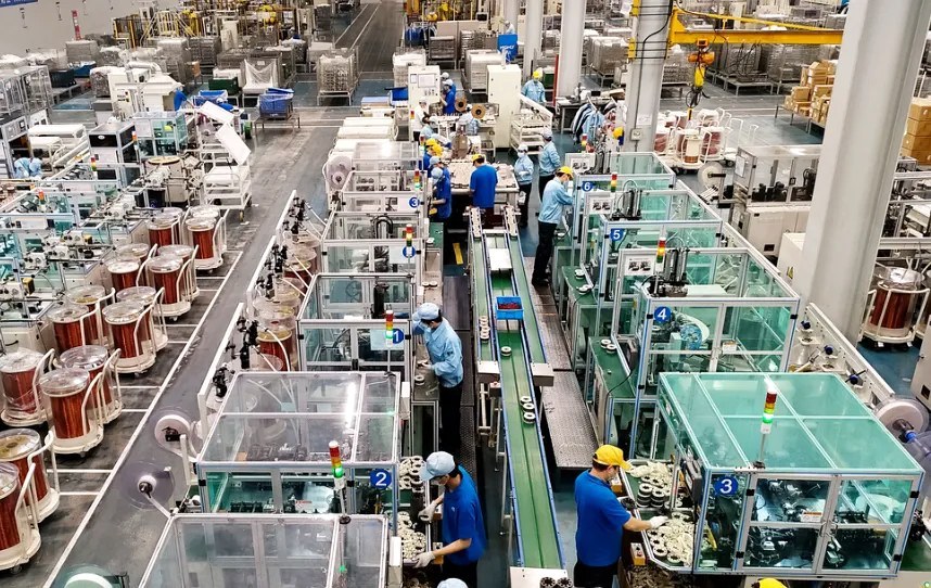 Interior of a Chinese manufacturing factory floor with workers and production machinery