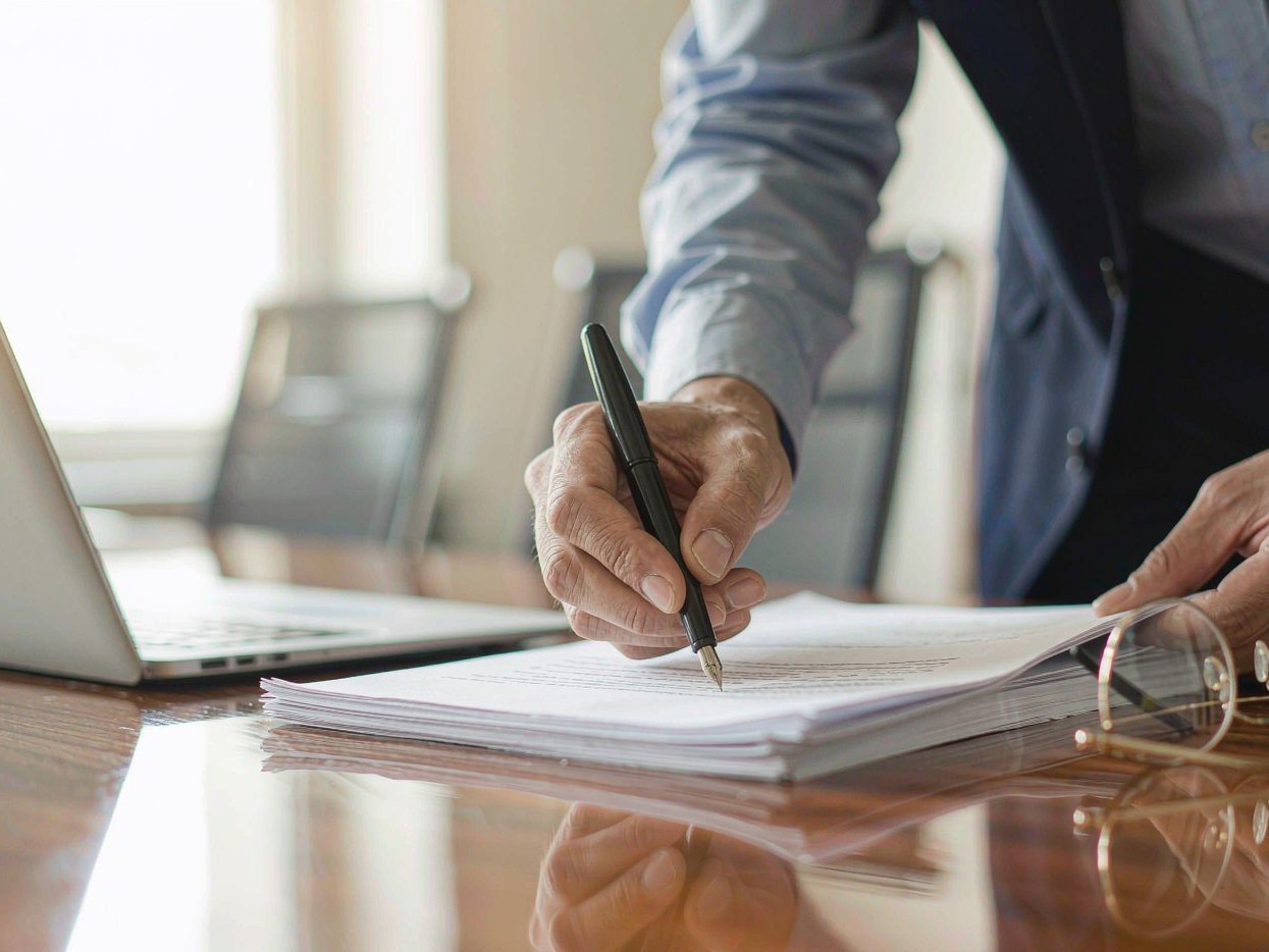 Businessman signing an anti-kickback agreement with a fountain pen on a polished desk