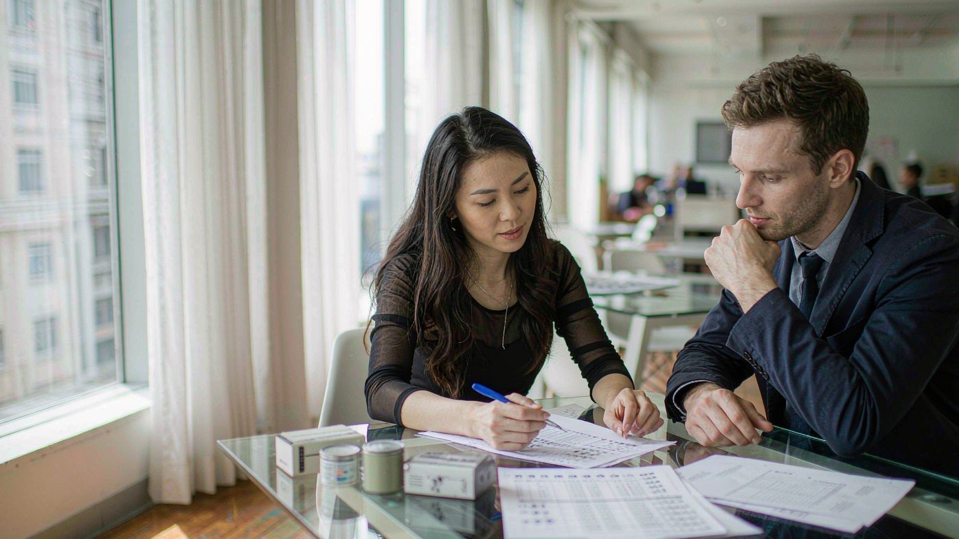 Professional sourcing meeting between buyer and agent reviewing supplier quotation in a modern bright office