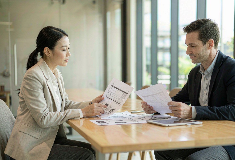 Two hands exchanging a stamped envelope on a polished desk