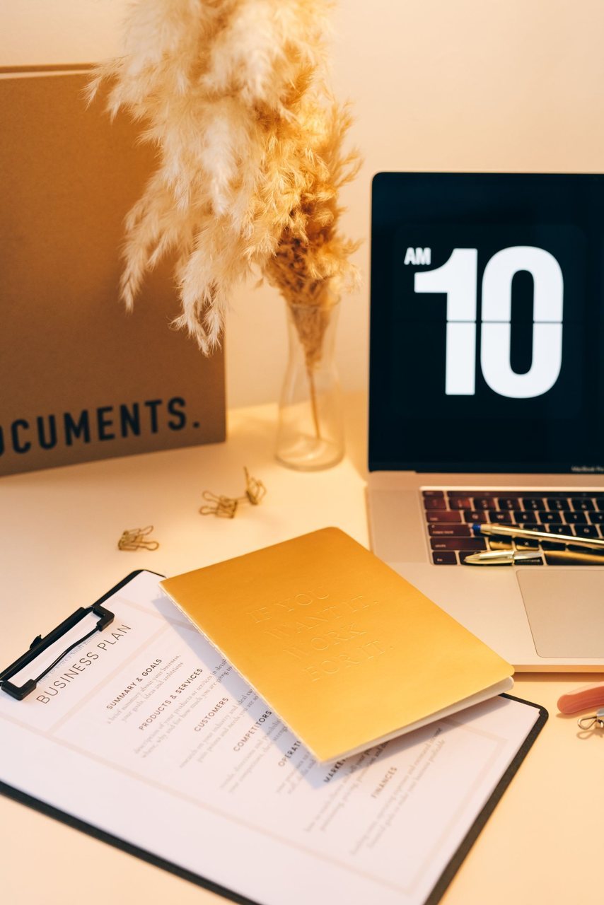 A desk with a laptop, business documents and a planning folder, representing the emissions-data RFQ preparation step.
