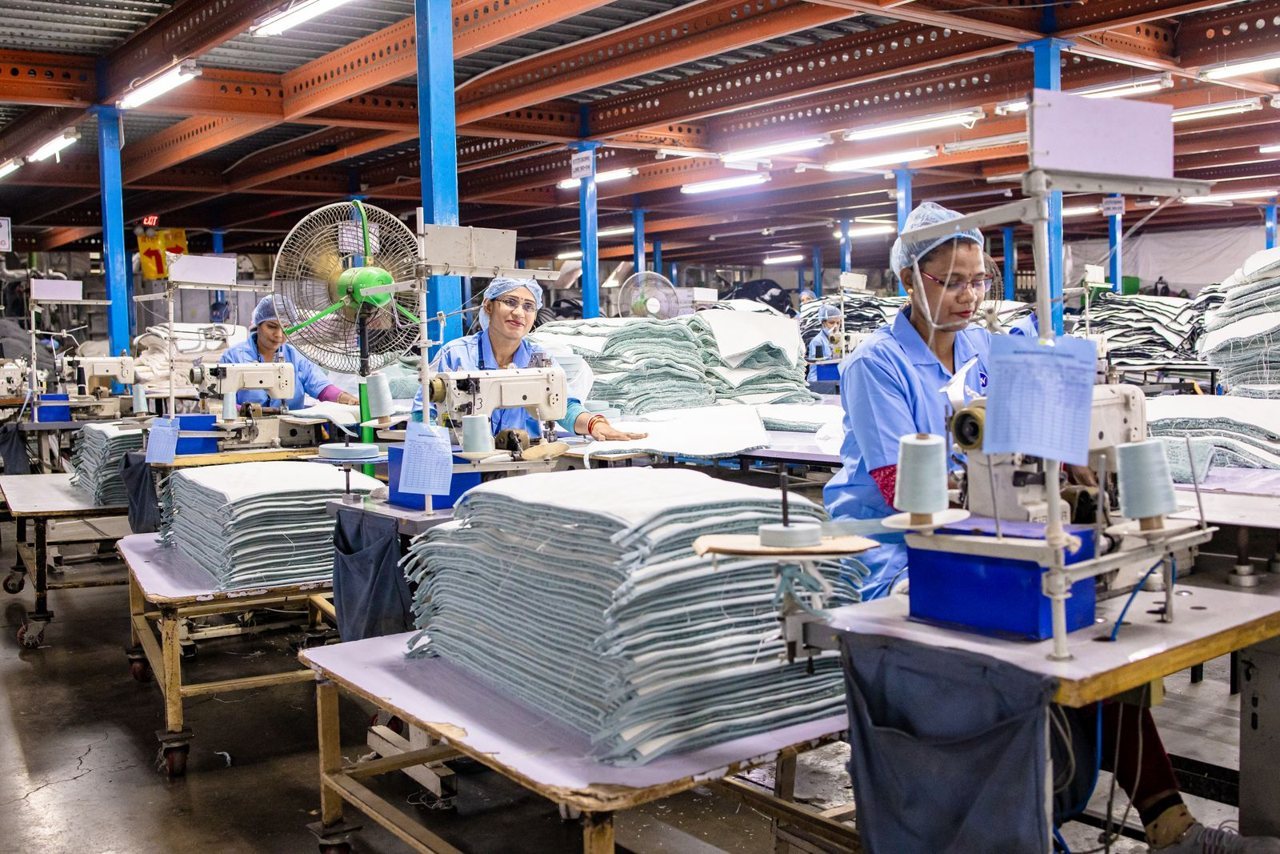Factory workers at sewing stations on a production floor, illustrating the labour, machine and overhead cost layers inside a should-cost model.