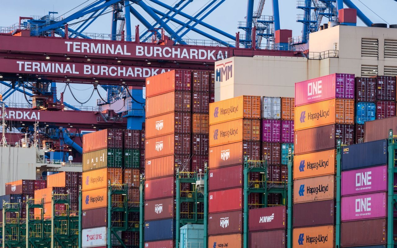 Stacked shipping containers and blue gantry cranes at a working container terminal, where export records become verifiable evidence of a supplier's real shipment volume.