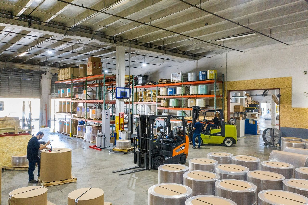 A finished-goods warehouse with forklifts working between racking aisles and stacked stock during normal operations.