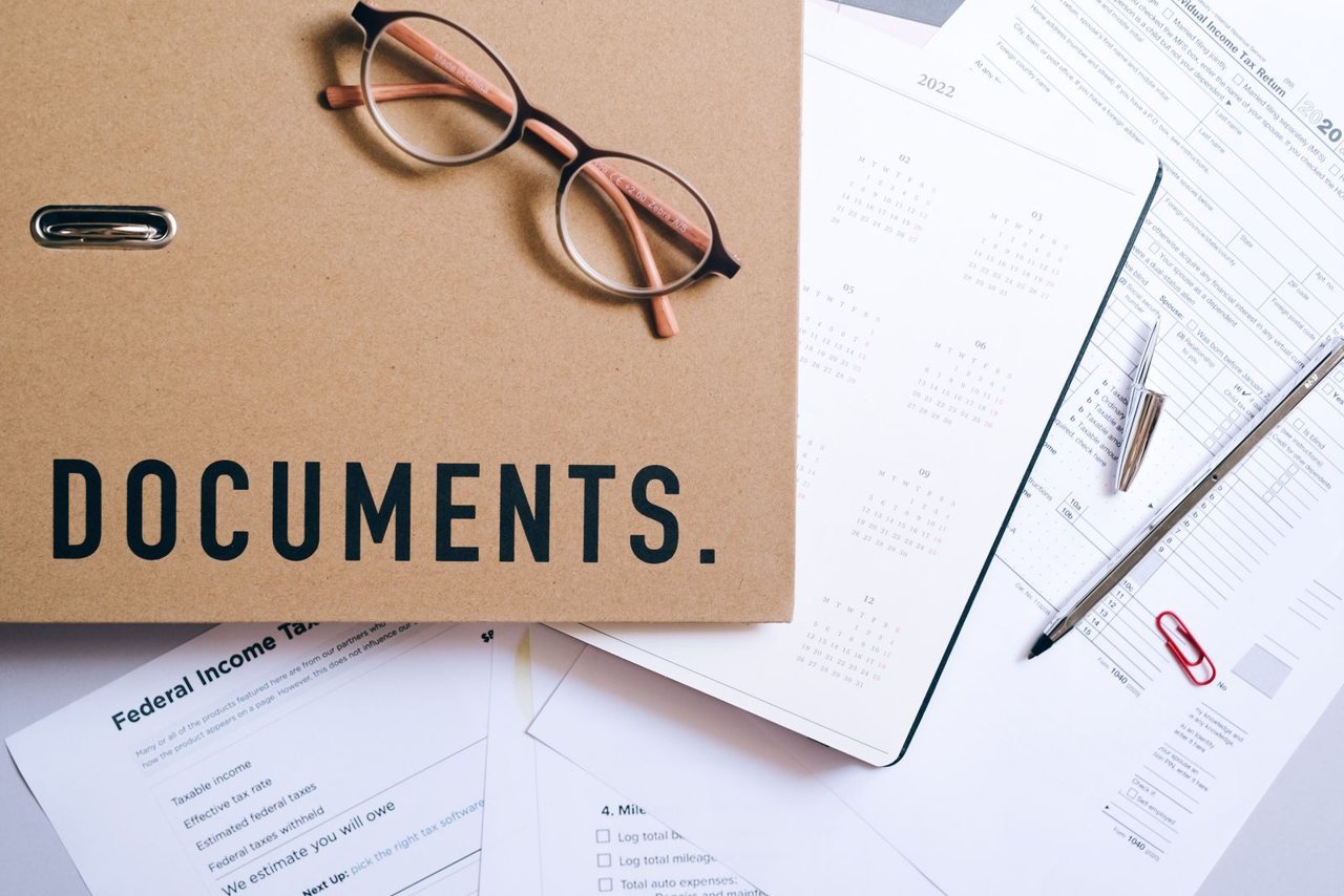 A folder of employee files, attendance sheets and payroll records laid out on a desk, the twelve months of documentation a social-compliance auditor reconciles before walking the floor