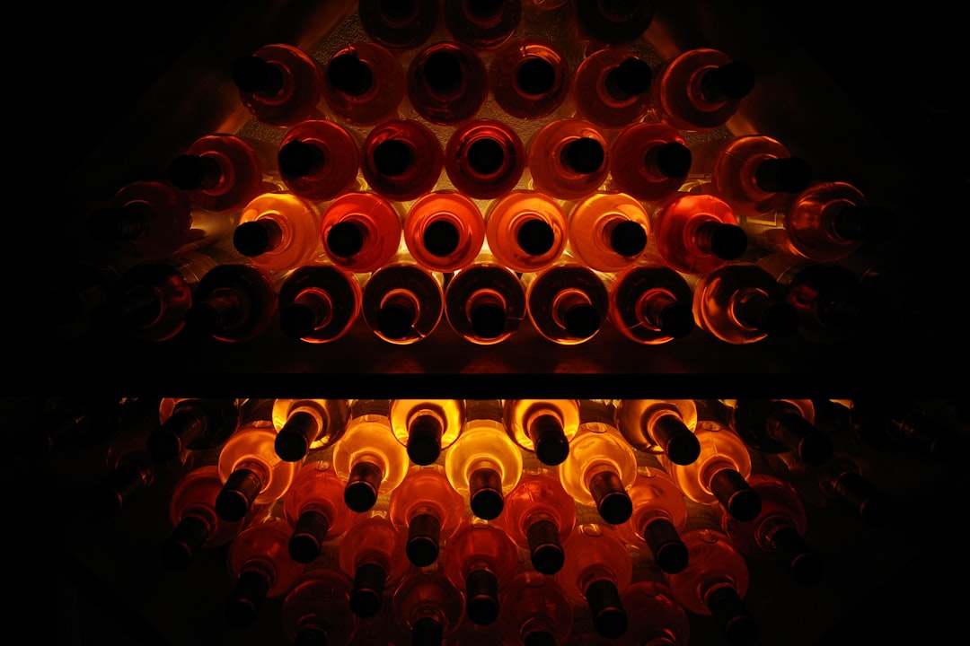 A collection of red and white wine bottles neatly arranged in a modern wine cooler with blue LED lighting