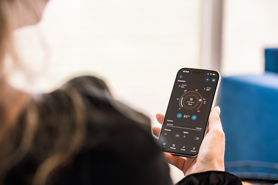 A person using a smartphone to adjust the settings on their smart dry aging fridge.