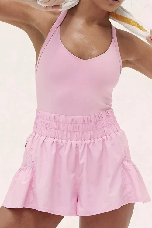 Sporty jumpsuit features a fitted top, loose fitting bottoms, short length, and slip-on design
