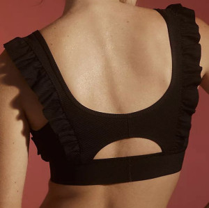 Women's sports bra features a supportive round neckline, wide straps accented with flirty ruffles and a cutout back.