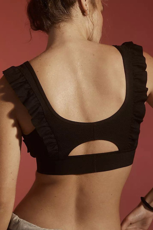 Women's sports bra features a supportive round neckline, wide straps accented with flirty ruffles and a cutout back.