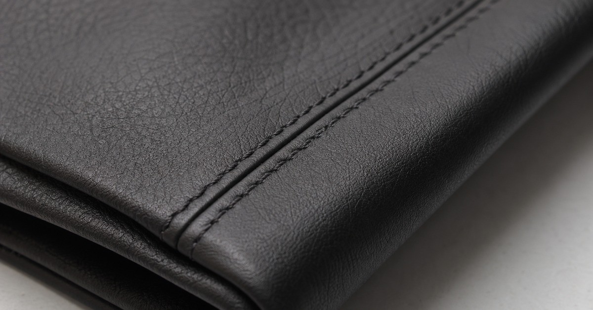 Close-up of a black leather jacket panel showing natural grain and a double-stitched seam for a leather jacket article