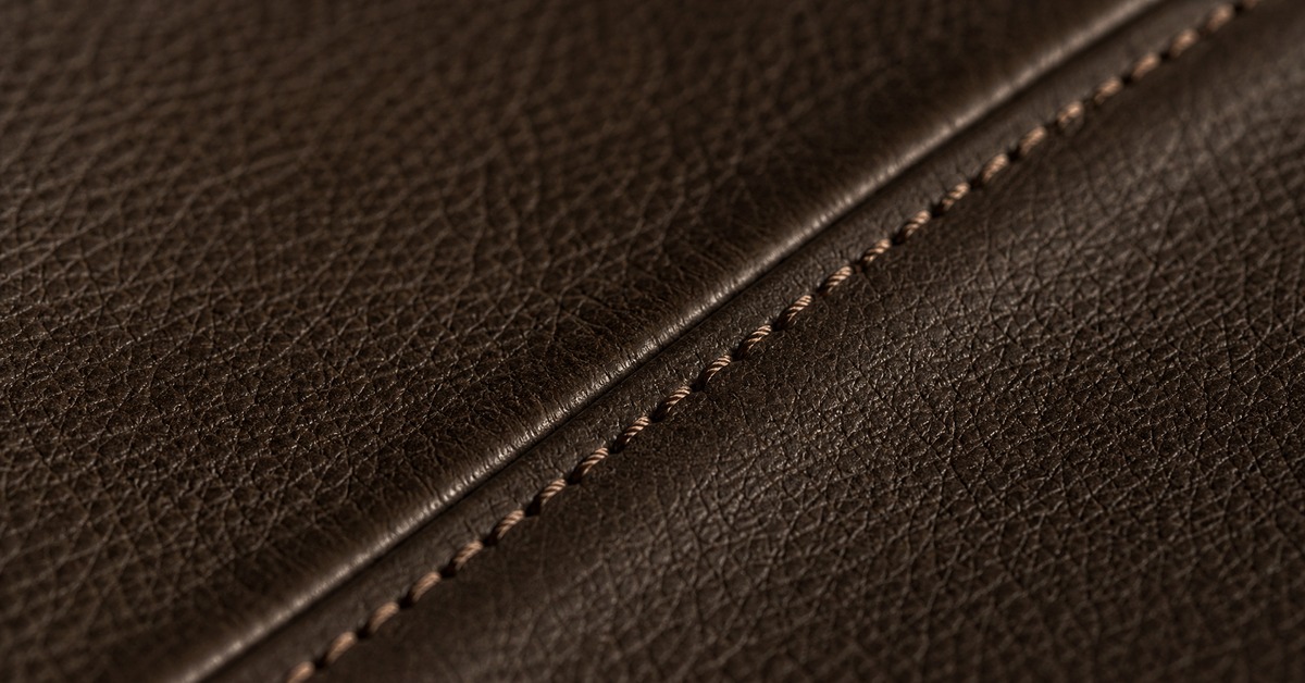 Macro view of even topstitching and grain texture across a finished dark brown leather jacket panel