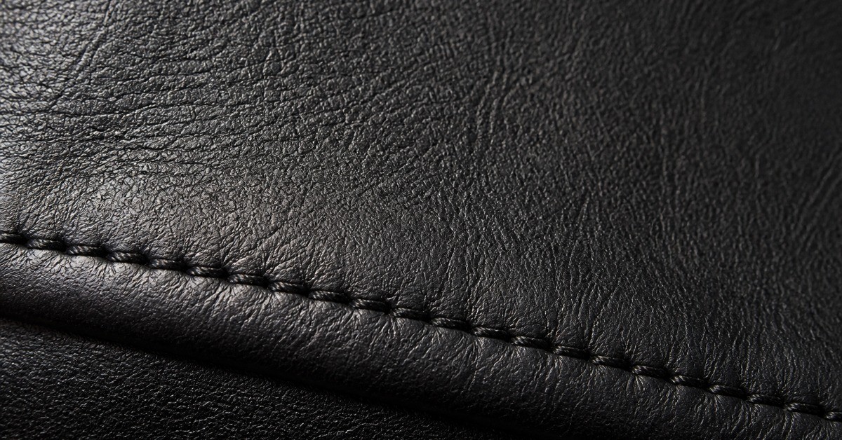 Close-up of black full-grain leather and a stitched seam on a men's leather jacket panel