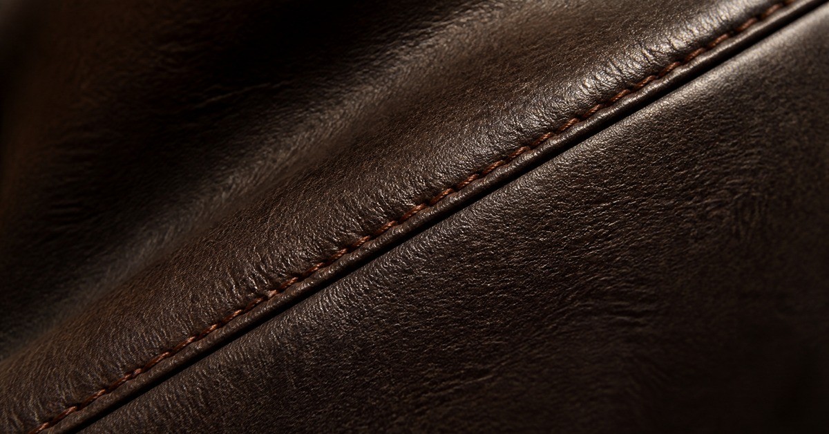 Close-up of dark brown leather jacket panel with topstitched seam for EU compliance feature