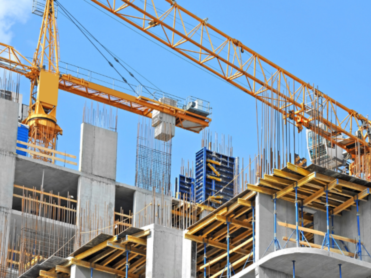 A worker using a digital tablet and laser tool on a construction site, representing technological integration