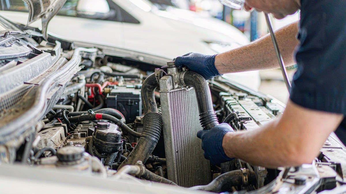 Technician installing a car radiator into the engine bay