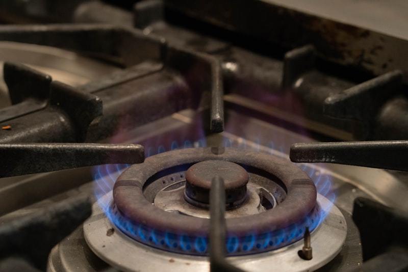 Close-up of a commercial gas stove burner with blue flames showing precise flame control