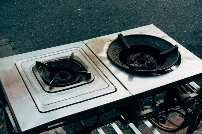 Two commercial gas stove burners sitting on a stainless steel table showing heavy-duty construction