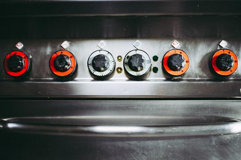 Close-up of a commercial gas stove with four burner knobs showing precise flame control mechanism