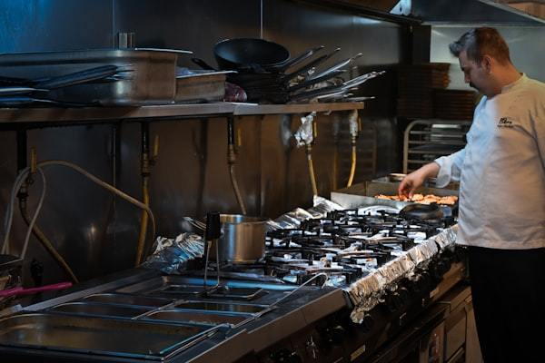 Chef cooking on a commercial gas stove in a professional restaurant kitchen