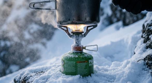 Camping stove showing weak flame and frost on fuel canister in cold weather