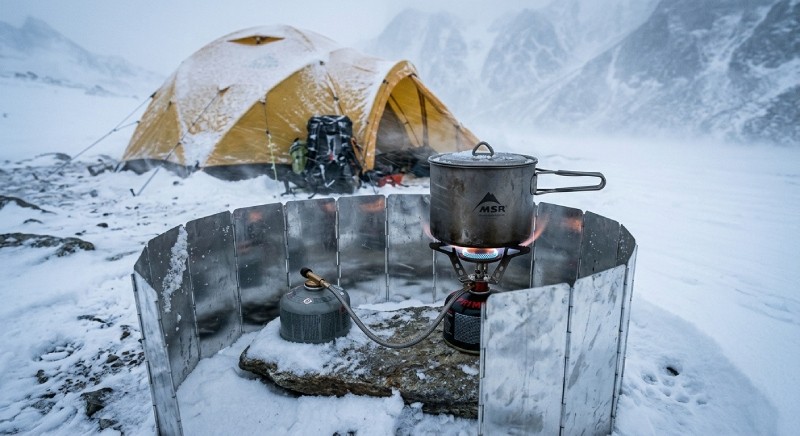 Wind effect on camping stove flame showing heat loss and reduced efficiency in winter conditions