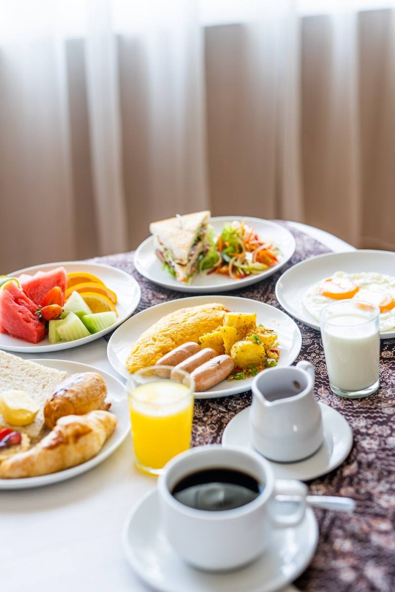assorted cooked breakfast foods and sliced fruits on buffet display