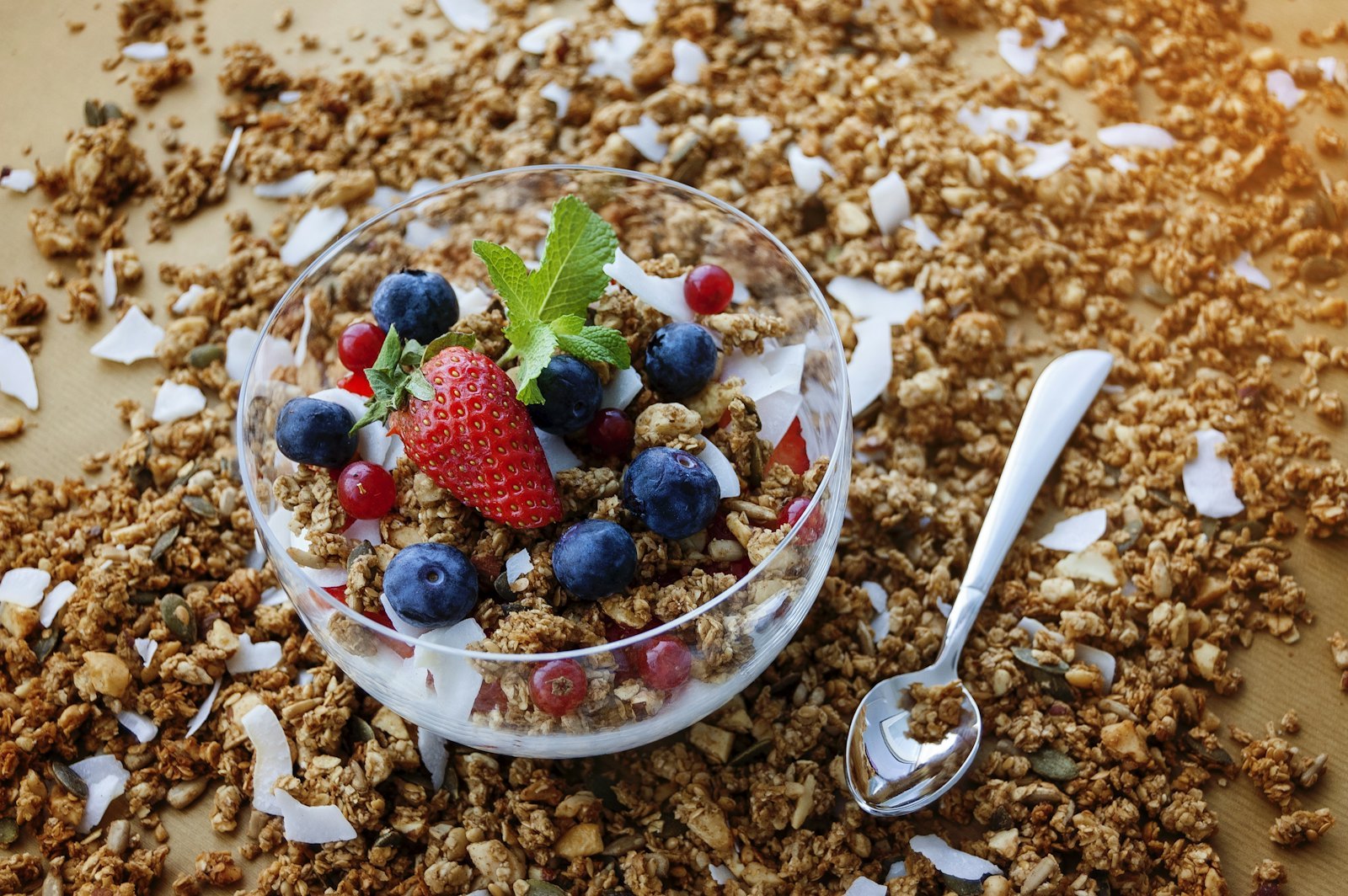 Granola and muesli served with fresh berries in a clear bowl at a breakfast buffet