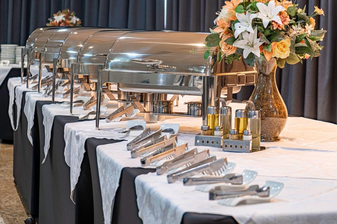 Chafing dish 4 quart roll-top unit beside a larger size chafing dish, stainless steel, lined up on a banquet buffet table