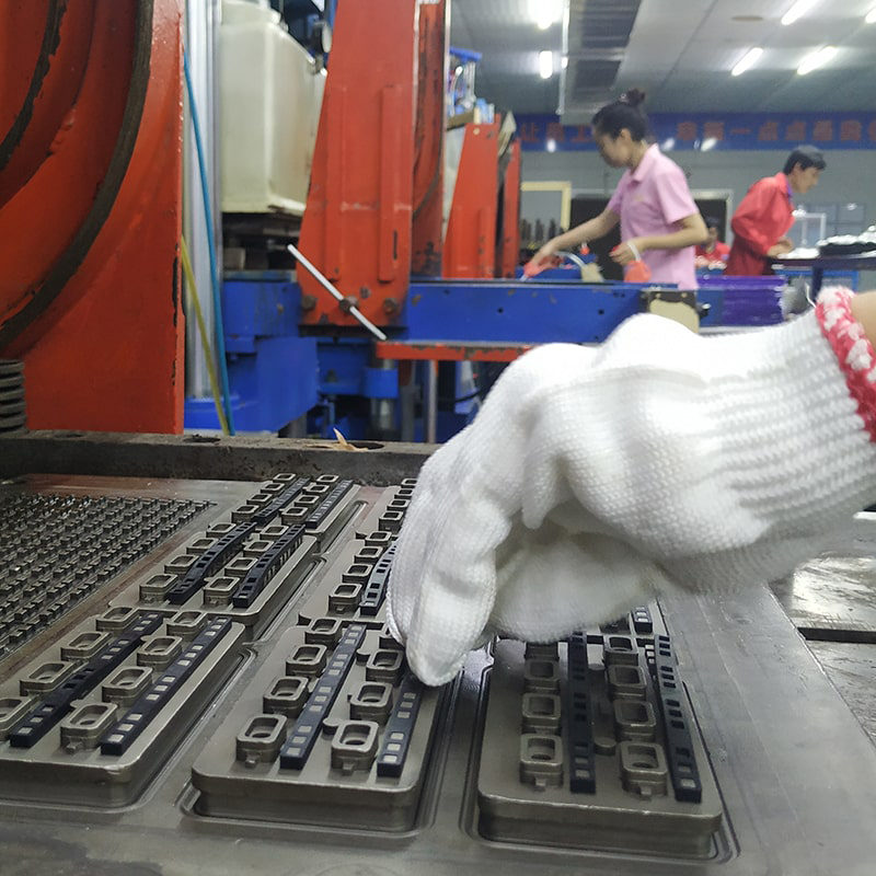 Technician loading silicone keypad preforms into a compression molding press at the FromRubber factory