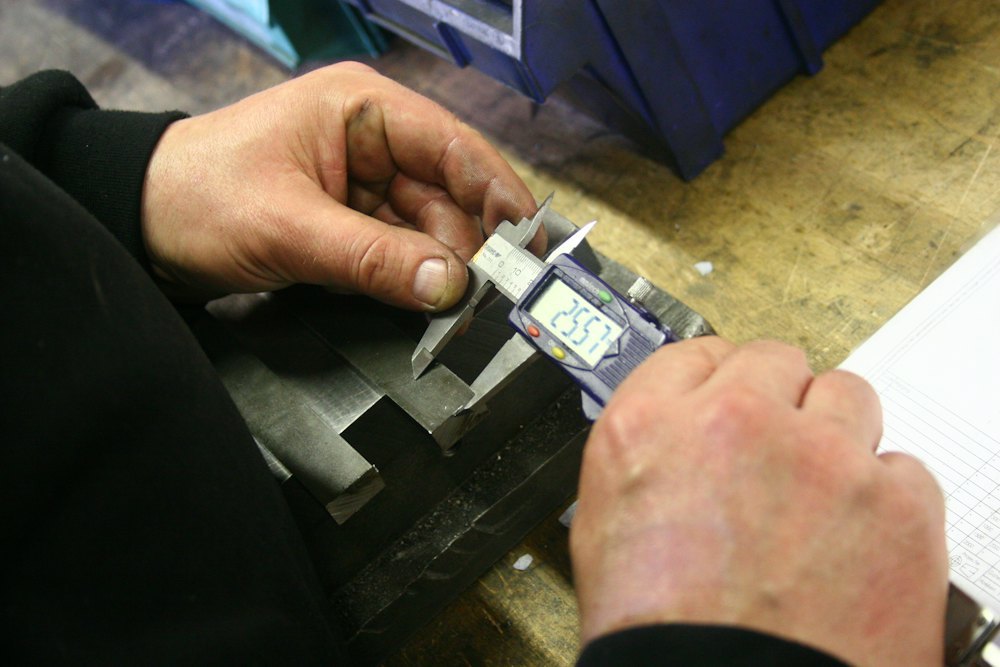 Engineer measuring a precision part with a digital caliper