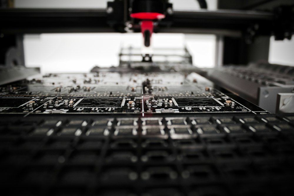 Automated robotic arm dispensing material onto a circuit board