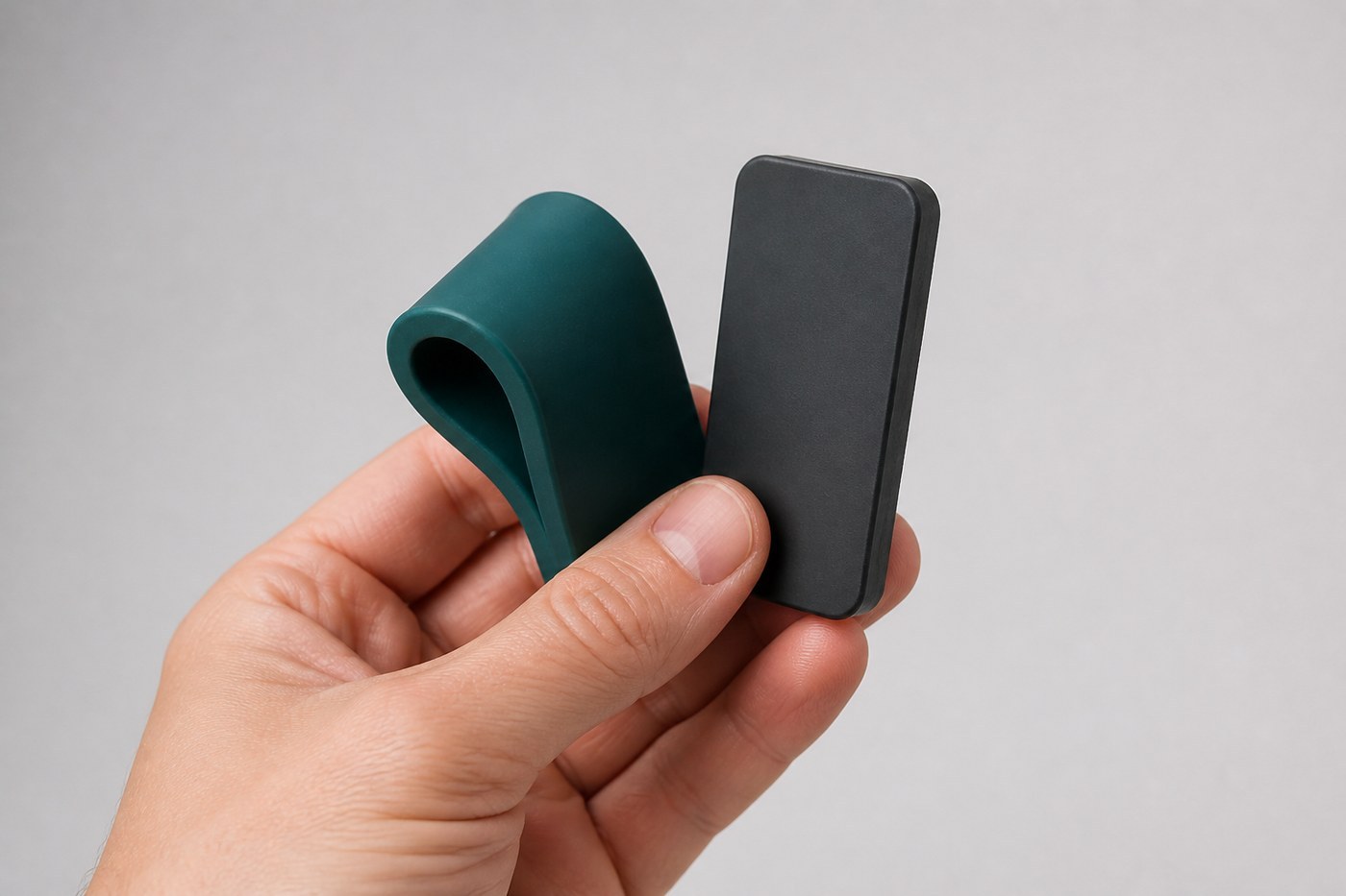 Two silicone patches held in one hand, one bending easily and one staying rigid, illustrating different silicone hardness