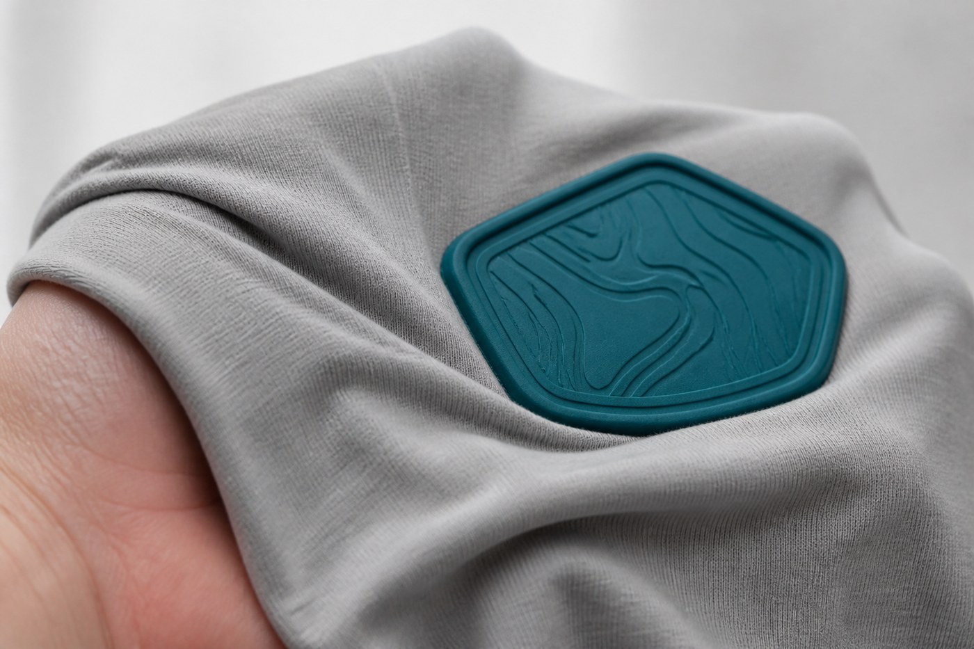 Silicone patch on thin grey stretch fabric forming a stiff zone while the surrounding knit folds