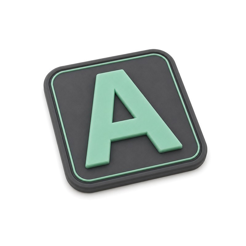 Small silicone logo on clothing with a hairline square frame beside a bold letter, showing how thin line detail behaves in a moulded silicone clothing patch